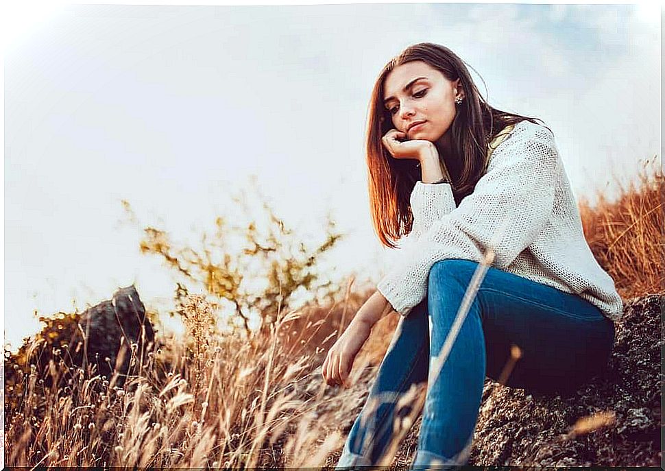 Woman sitting in a field controlling anxiety