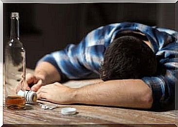 A man asleep on a table who has drunk a whole bottle of alcohol. 