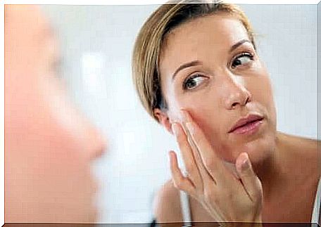 A woman putting cream on her face.