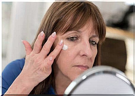 A woman applying cream to her face. 